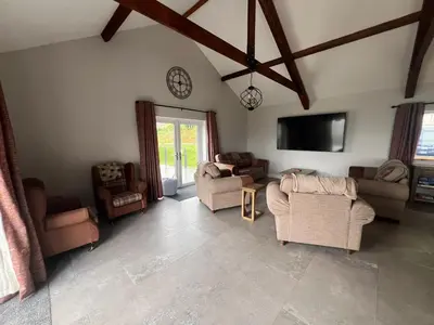 a living room with couches and chairs and a tv at Llwynblyfyn in Llandeilo