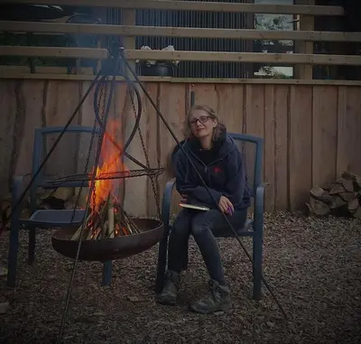 a woman sitting in a chair next to a fire at Fronfetyn in Aberystwyth