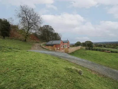 a house in a field next to a dirt road at Border View Lodge in Welshpool