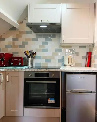 a kitchen with white cabinets and an oven at Trem Y Mor - Edge of the Sea in Tywyn