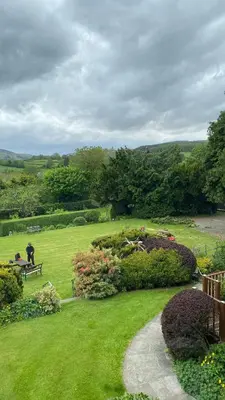 a garden with a person sitting on a bench in the grass at Penralley House B&B in Rhayader