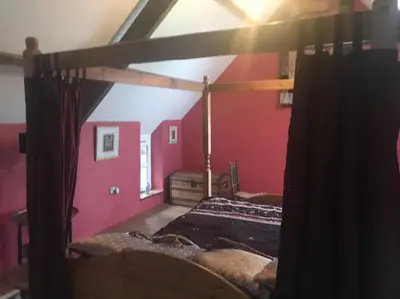 a bed in a room with a red wall at Ysgubor y Tanybryn The barn with a view and a spa. in Tregaron