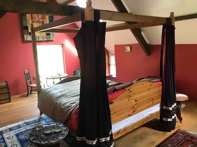 a bedroom with a bed in a room with red walls at Ysgubor y Tanybryn The barn with a view and a spa. in Tregaron