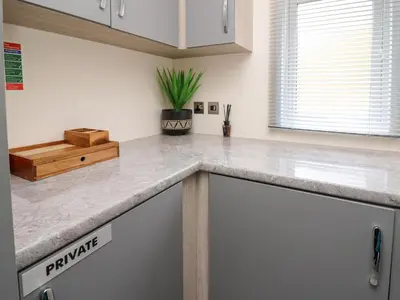 a kitchen with white cabinets and a counter top at 43 The Deri in New Quay