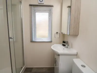 a white bathroom with a sink and a mirror at 43 The Deri in New Quay