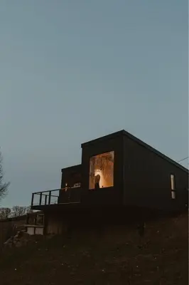 a black house with a window on the side of it at 3 x bespoke built cabins with hot tubs, mid Wales in Newtown