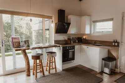 a kitchen with white cabinets and a counter with stools at 3 x bespoke built cabins with hot tubs, mid Wales in Newtown