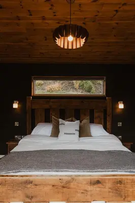 a bedroom with a large bed with a window at 3 x bespoke built cabins with hot tubs, mid Wales in Newtown