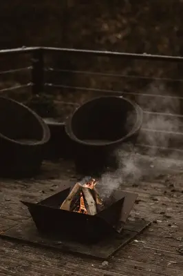 a grill with a fire in it with smoke at 3 x bespoke built cabins with hot tubs, mid Wales in Newtown