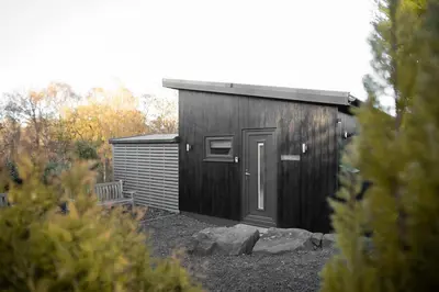 a black shed with a door in a yard at 3 x bespoke built cabins with hot tubs, mid Wales in Newtown