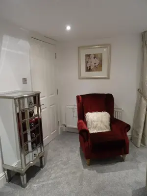 a living room with a red chair and a cabinet at Ty Ni Holiday Apartment Aberdovey in Aberdyfi