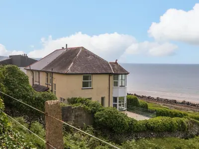 a house on a hill next to the ocean at Morolwg in Barmouth