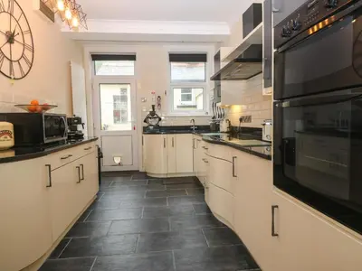 a large kitchen with white cabinets and black appliances at Morolwg in Barmouth