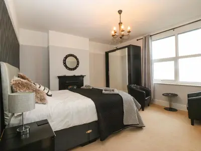 a bedroom with a bed and a chair and a mirror at Morolwg in Barmouth