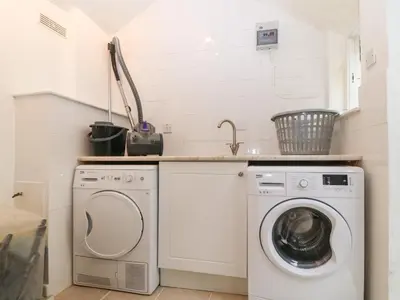 a laundry room with a washing machine and a sink at Morolwg in Barmouth