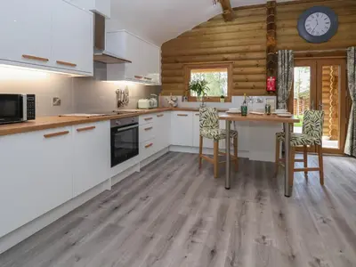 a kitchen with white cabinets and a wooden wall at Redwood Lodge in Ellesmere