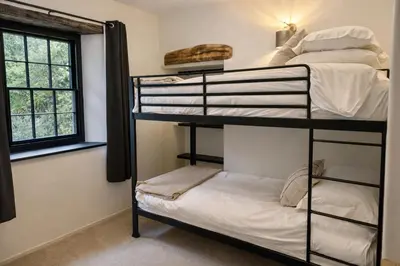 a room with three bunk beds and a window at Glandwr Lodge, 3 bed in Barmouth, Wales in Barmouth