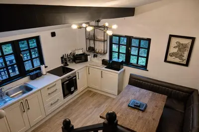 a kitchen with white cabinets and a wooden table at Glandwr Lodge, 3 bed in Barmouth, Wales in Barmouth