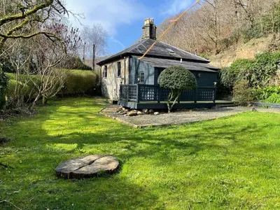 a small house in a yard with a green lawn at Glandwr Lodge, 3 bed in Barmouth, Wales in Barmouth