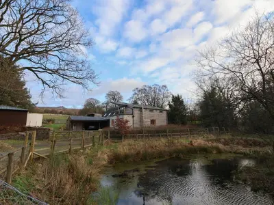 a barn and a pond in front of a house at The Chicken Coop in Shrewsbury
