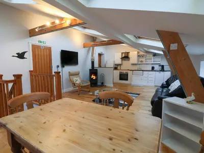 a living room with a wooden table and a kitchen at The Duckhouse in Shrewsbury