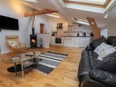 a living room with a leather couch and a fireplace at The Duckhouse in Shrewsbury