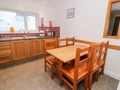 a kitchen with a wooden table and chairs and a sink at Borthwen in Barmouth