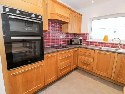 a kitchen with wooden cabinets and black appliances at Borthwen in Barmouth