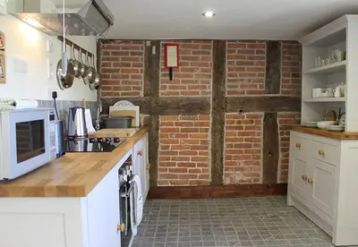 a kitchen with a brick wall and white appliances at Dee's Cottage at Brinsop in Hereford