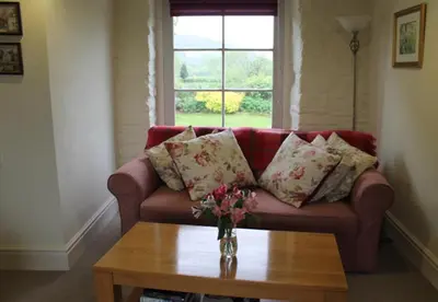 a living room with a couch with pillows and a table at Dee's Cottage at Brinsop in Hereford