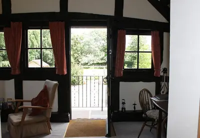an open door to a room with a chair and a table at Cider Press in Hereford