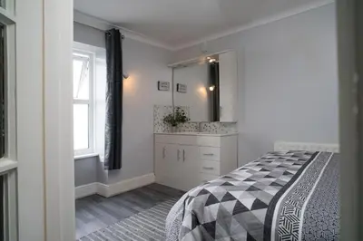 a bedroom with a bed and a sink and a mirror at Min y Graig New Quay in New Quay