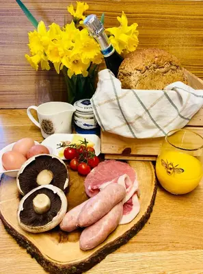 a table with eggs sausage and bread and a bottle of wine at Luxury Stargazing Glamping - Seren Aur with Hot Tub in Llanidloes