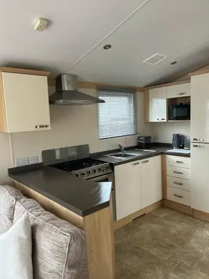 a kitchen with white cabinets and a black counter top at Harries Lodge 2 Aberaeron in Aberaeron