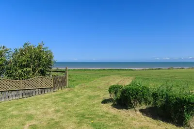a fence in a field with the ocean in the background at Swn y Mor Aberaeron in Aberaeron