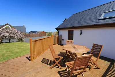 a wooden deck with a wooden table and chairs at Swn y Mor Aberaeron in Aberaeron
