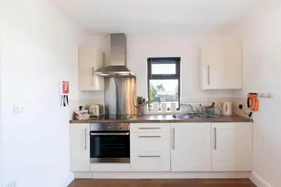 a kitchen with white cabinets and a sink at Seabreeze Aberaeron in Aberaeron