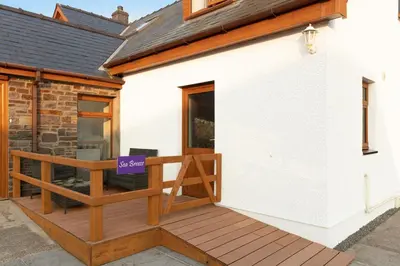 a house with a deck with a purple sign on it at Seabreeze Aberaeron in Aberaeron