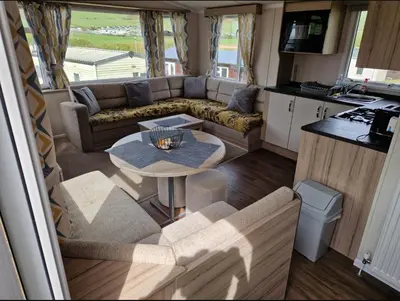 an rv living room with a couch and a table at Experience Coastal Bliss in Our Modern 2019 Sea Viev 2 Bedroom static caravan at Clarach Bay Holiday Village! in Aberystwyth