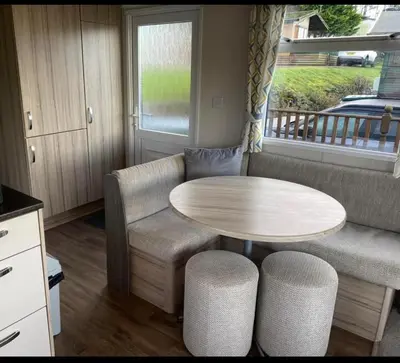 a kitchen with a table and a table and chairs at Experience Coastal Bliss in Our Modern 2019 Sea Viev 2 Bedroom static caravan at Clarach Bay Holiday Village! in Aberystwyth