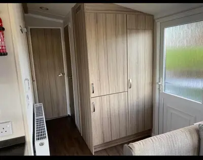 a room with wooden cabinets and a window at Experience Coastal Bliss in Our Modern 2019 Sea Viev 2 Bedroom static caravan at Clarach Bay Holiday Village! in Aberystwyth