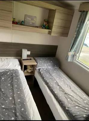 a bedroom with two beds and a desk with a laptop at Experience Coastal Bliss in Our Modern 2019 Sea Viev 2 Bedroom static caravan at Clarach Bay Holiday Village! in Aberystwyth