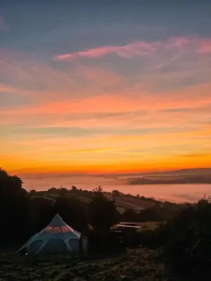 a tent on a hill with a sunset in the background at Luxury Stargazing Glamping - Seren Hardd with Hot Tub in Llanidloes