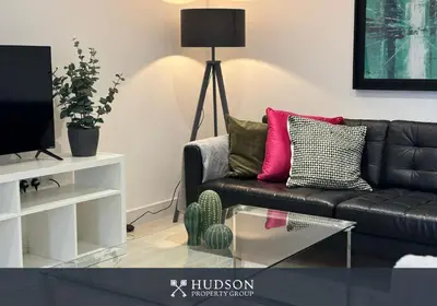 a living room with a black couch and a tv at Shrewsbury Townhouse with 3 En-suites in Shrewsbury