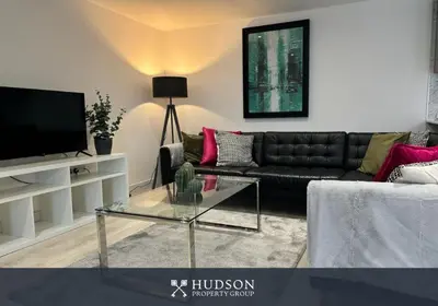 a living room with a black couch and a glass table at Shrewsbury Townhouse with 3 En-suites in Shrewsbury