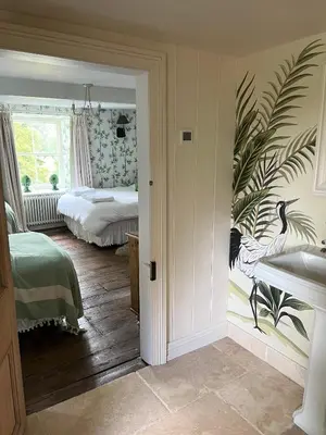 a bedroom with two beds and a wall with a peacock mural at The Pink House in Brecon