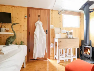 a bedroom with a bed and a room with a fireplace at Red Kite at Wild Valley Huts in Oswestry
