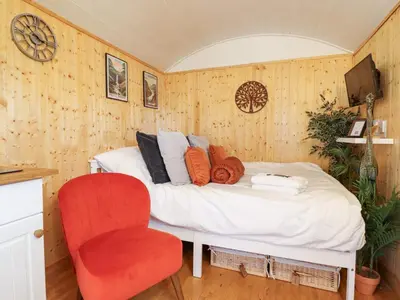a bedroom with a bed and a red chair at Red Kite at Wild Valley Huts in Oswestry