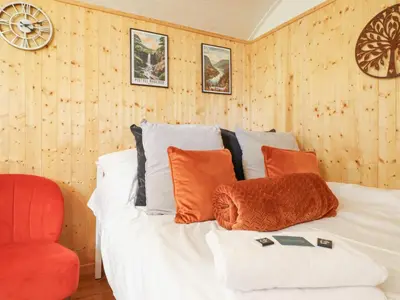 a bedroom with a white bed and a red chair at Red Kite at Wild Valley Huts in Oswestry