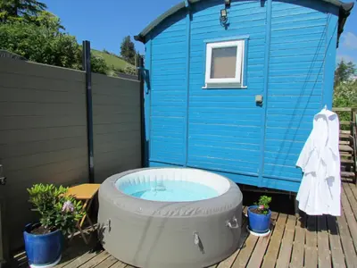 a blue shed with a hot tub on a deck at Cuckoo at Wild Valley Huts in Oswestry